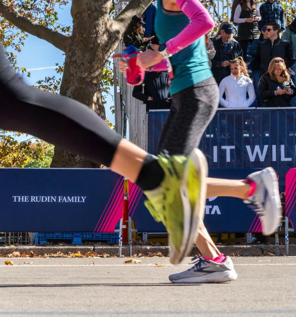 Marathon runners passing in front of Rudin signage  
