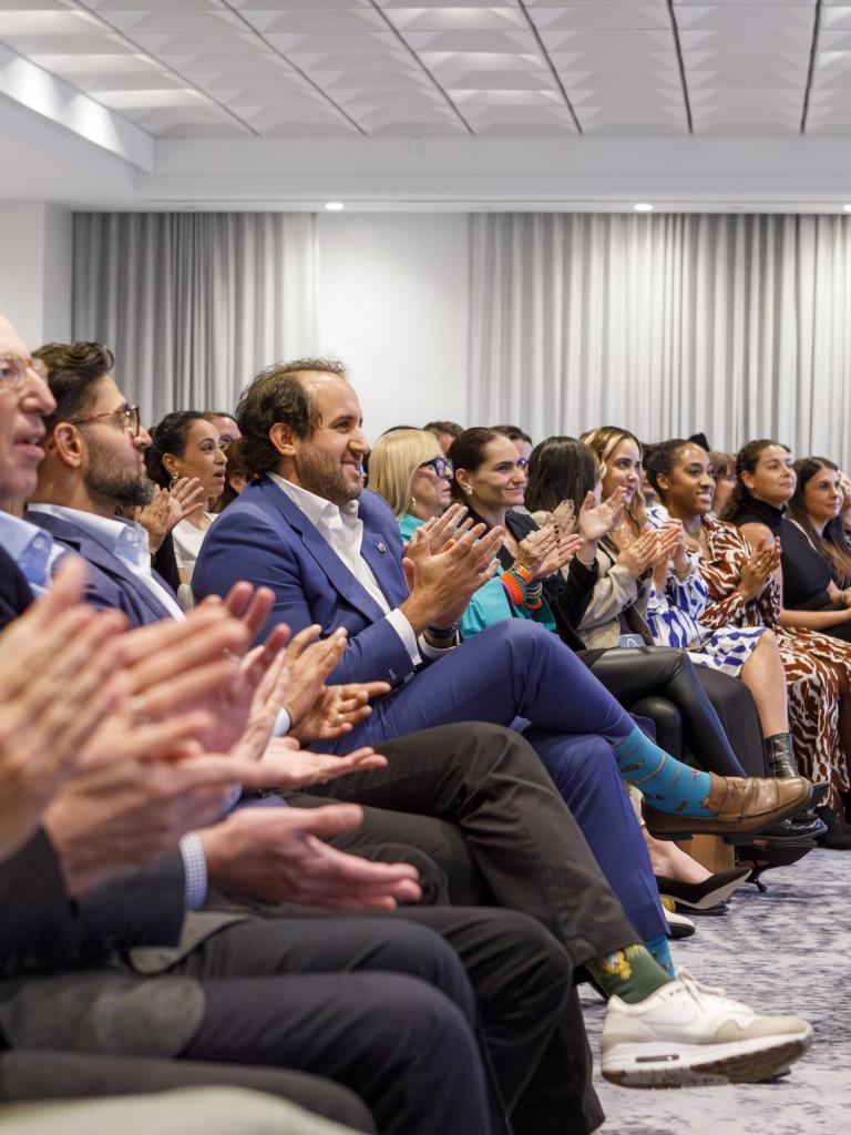 Rudin team members clapping in the audience of a company Town Hall event