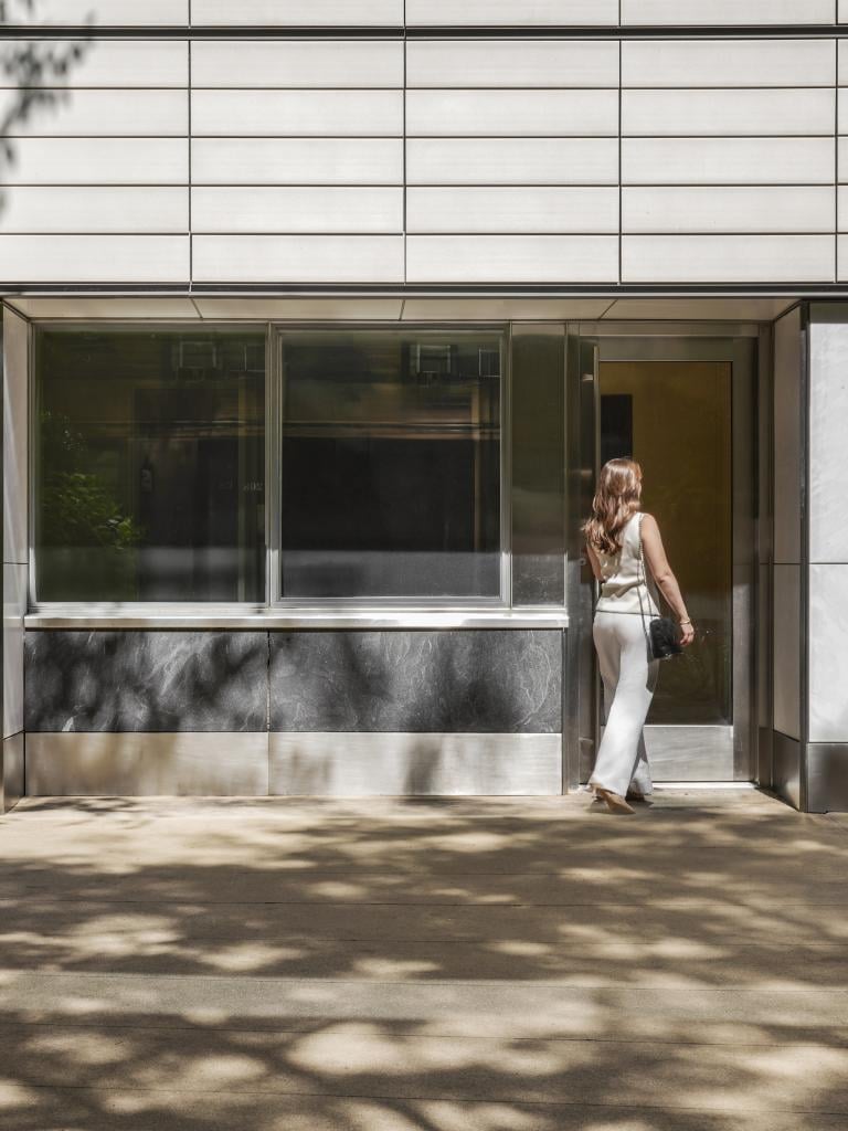 A woman in business clothing enters an office building from the street