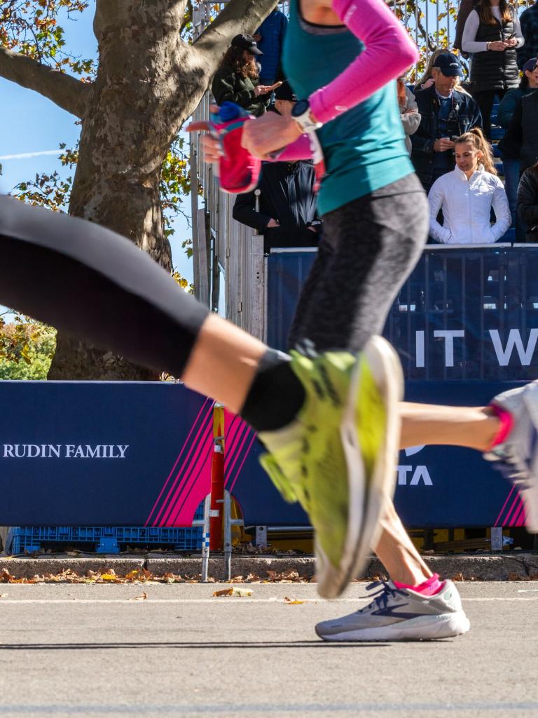 Marathon runners passing in front of Rudin signage  