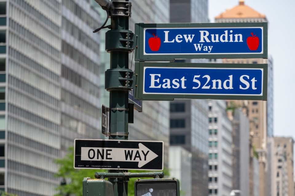 A street sign in NYC showing Lew Rudin Way and East 52nd Street