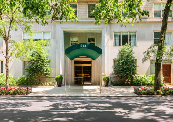 Across the street is a sidewalk with greenery and the entrance to 945 Park Avenue