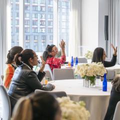 A group sits at tables listening to a presentation