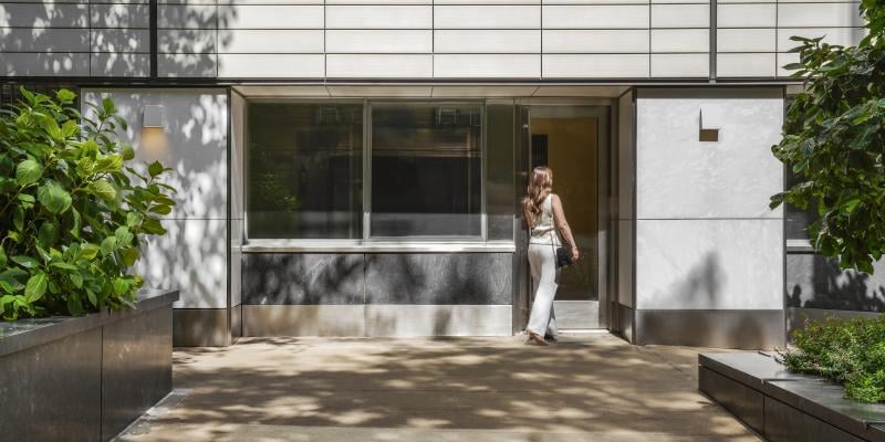 A woman in business clothing enters an office building from the street