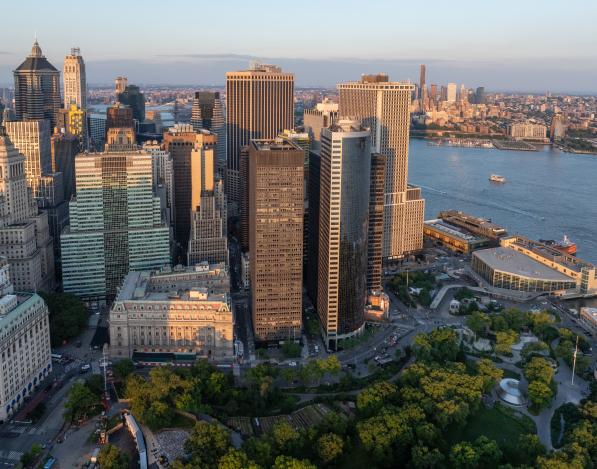 An aerial view of 1 Battery Park Plaza surrounded by other buildings with Battery Park below and water in the background