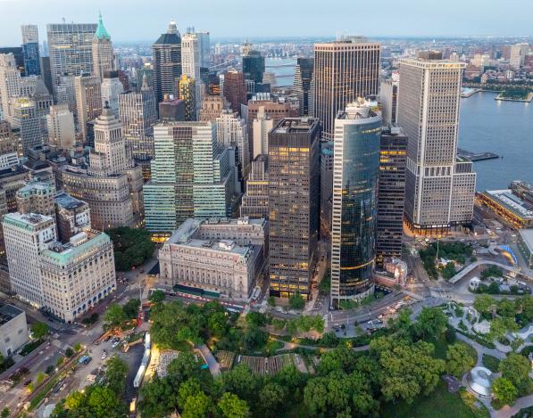 An aerial view of 1 Battery Park Plaza surrounded by other buildings with Battery Park below and water in the background