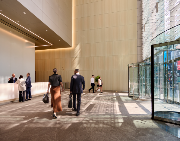 The ground floor of an office building with high ceilings, tall windows, and office workers
