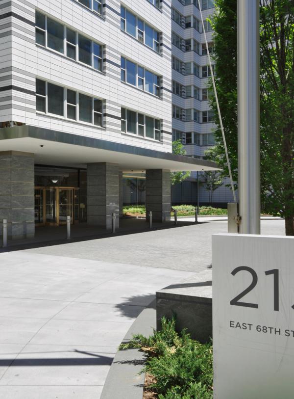 A sign for 215 East 58th Street sits in front of the apartment building's entrance