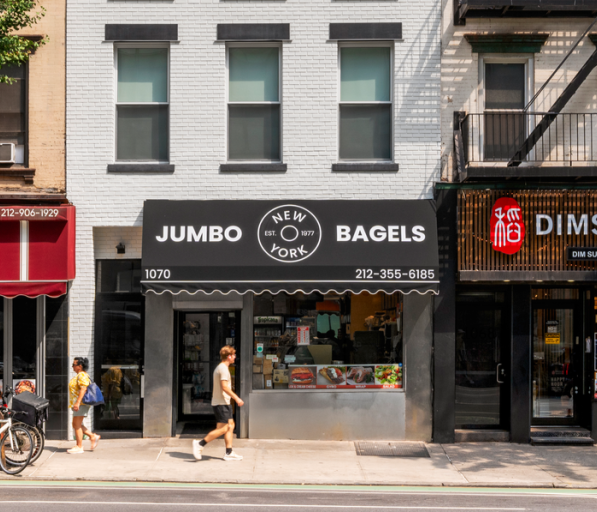 A street view of three retail spaces from a sidewalk with trees