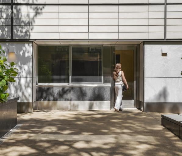 A woman in business clothing enters an office building from the street